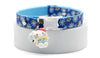 Cat collar with blue floral pattern and cartoon character charm on a white background