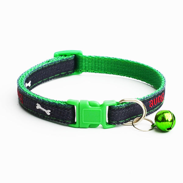 A green and black dog collar with a bright green plastic buckle, a small shiny green bell, and white bone graphics on a white background.
