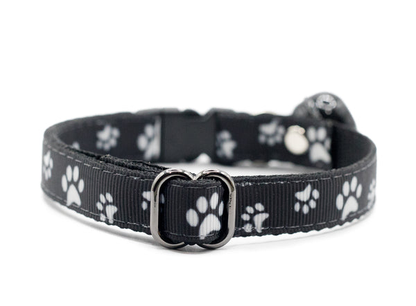 Black puppy collar with white paw print pattern on a white background