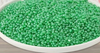 Green beads in a white bowl on a wooden surface