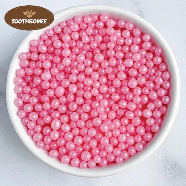 White bowl filled with pink pearls on a light gray background