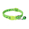 A lime green dog collar with a repeating pattern of blue and white bones, featuring a matching lime green plastic buckle and a small shiny green bell with a black skull design.