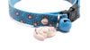 Blue cat collar with a pink cat charm and bell on a white background