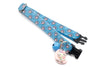 Blue pet collar with pink paw prints and a Hello Kitty charm on a white background