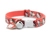 Red polka dot cat collar with white buckle and bell on a white background